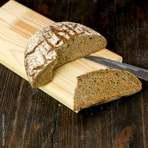 black bread on a brown background,a knife in the bread,cut black bread