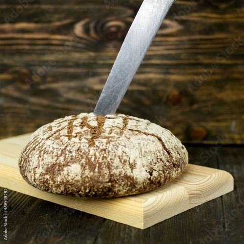 black bread on a brown background,a knife in the bread