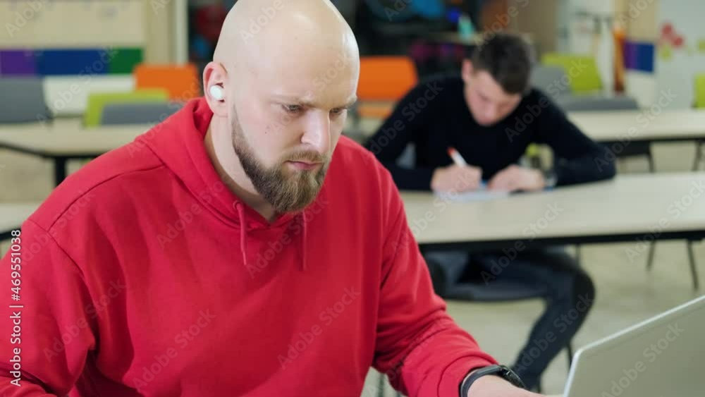 Young man that is learning robotics lessons using computer, behind him his colleague write in their notebook lessons notice. Young man that is learning robotics lessons using computer, behind him his colleague write in their notebook lessons notice.