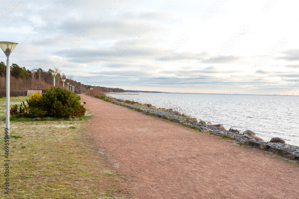 Walking sandy path along the seashore. An empty sea embankment on an autumn day Walking sandy path along the seashore. An empty sea embankment on an autumn day