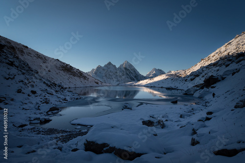 A high mountain lake against the backdrop of snow-covered peaks at sunrise in Karachay-Cherkessia