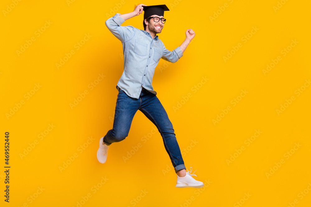 Full length profile side photo of young man happy positive smile jump go run master degree isolated over yellow color background Full length profile side photo of young man happy positive smile jump go run master degree isolated over yellow color background