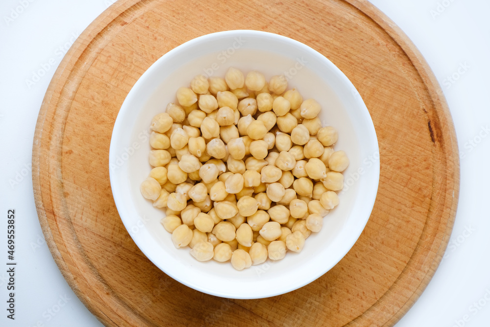 Fresh raw organic chickpeas soaked in water on a white table on a wooden tray. The benefits of legumes. Vegan nutritive proteinaceous food. Taking care of your health. Empty space. Fresh raw organic chickpeas soaked in water on a white table on a wooden tray. The benefits of legumes. Vegan nutritive proteinaceous food. Taking care of your health. Empty space.