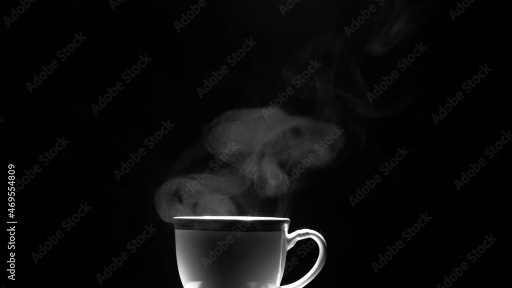 White ceramic hot coffee cup with steam float up from cup on dark background with film grain from heat from steam, slow motion, hot drink concept White ceramic hot coffee cup with steam float up from cup on dark background with film grain from heat from steam, slow motion, hot drink concept