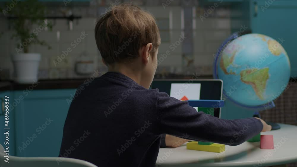 Autistic boy building with color wooden blocks using tablet computer