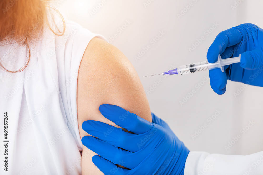 Close up of female patient taking vaccine from qualified doctor at modern clinic. Concept of vaccination process, prevention and protection. Close up of female patient taking vaccine from qualified doctor at modern clinic. Concept of vaccination process, prevention and protection.