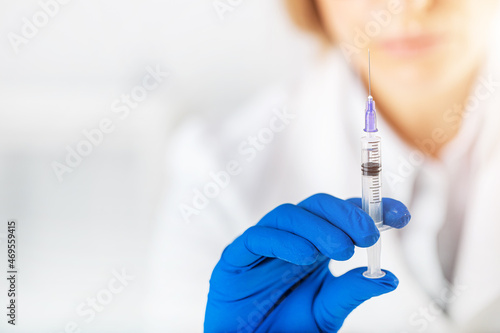 Female doctor in gloves holding syringe with vaccine. Injection for virus protection. Health care and medicine concept.