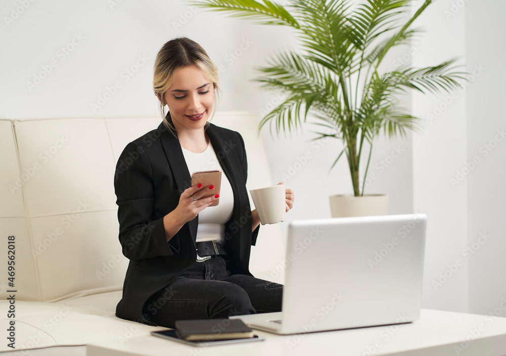 young woman checks her smartphone messages while having coffee before starting work young woman checks her smartphone messages while having coffee before starting work