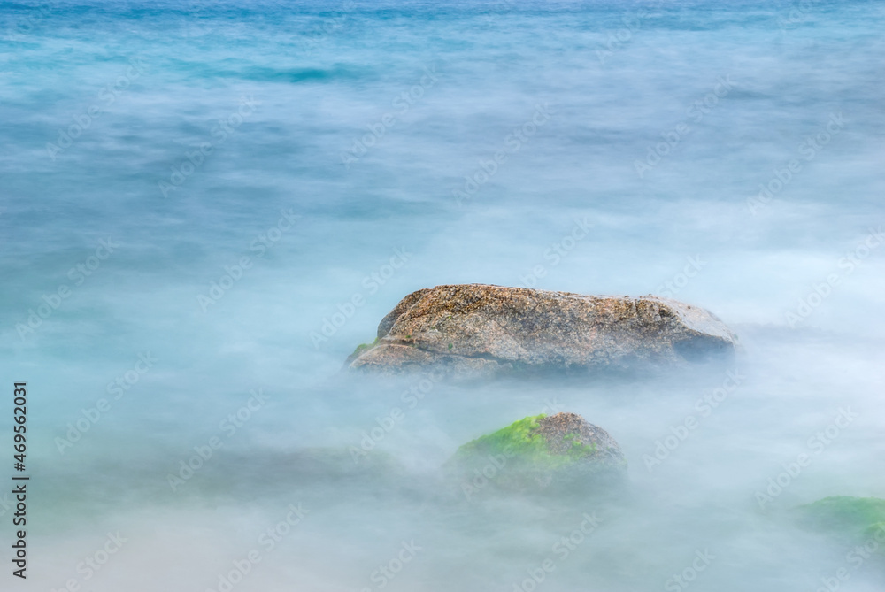 Fototapeta premium Sea stones in the water of the Mediterranean Sea. Water creates fog due to long exposure.