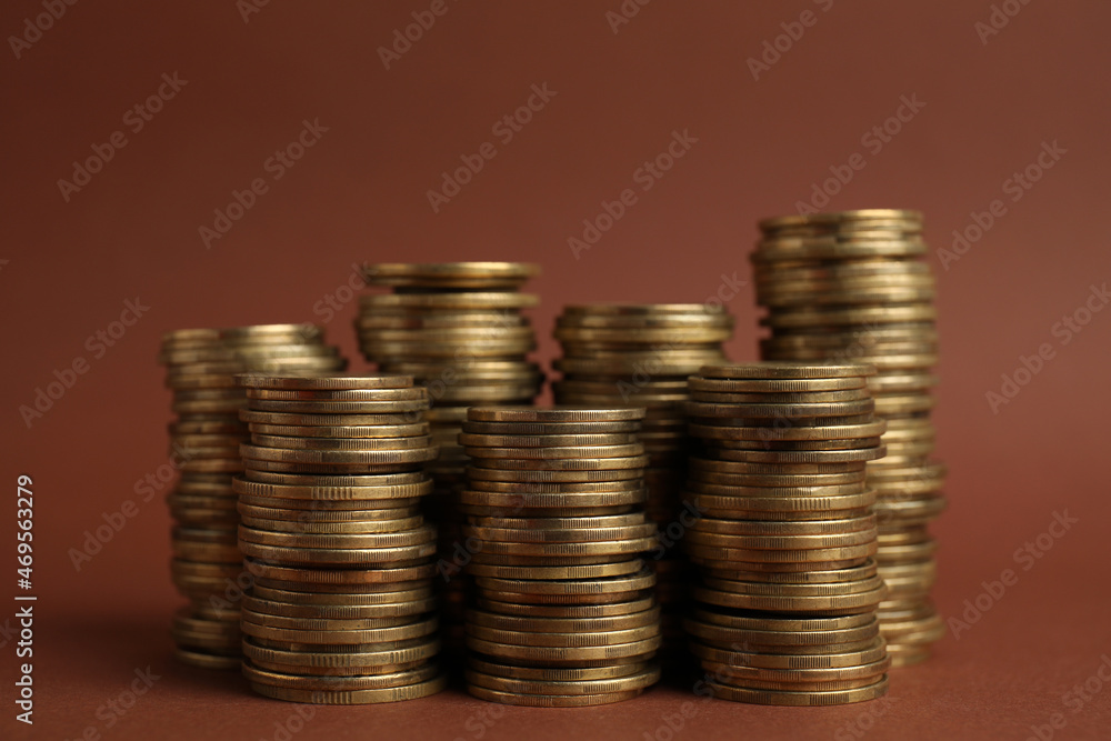 Many golden coins stacked on brown background Many golden coins stacked on brown background
