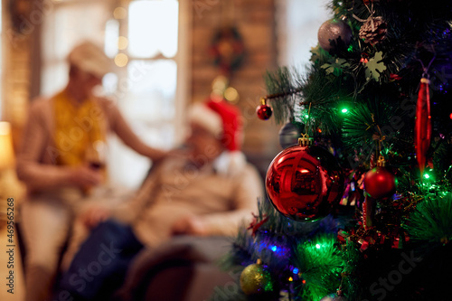 Close-up of decorated Christmas tree with senior couple in the background.