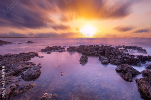 Long exposure sea sunset, blurry clouds, coastal stones.