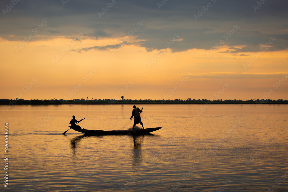 Naklejka premium A man rowing on river niger in Africa trying to catch fish