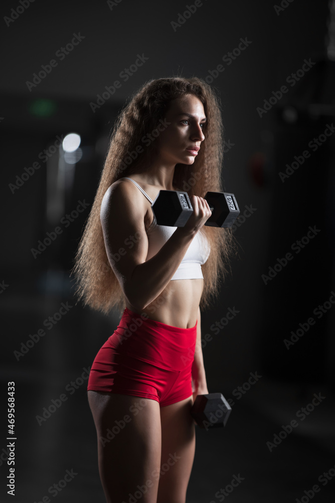 Fit woman doing exercise with dumbbells in the gym Fit woman doing exercise with dumbbells in the gym