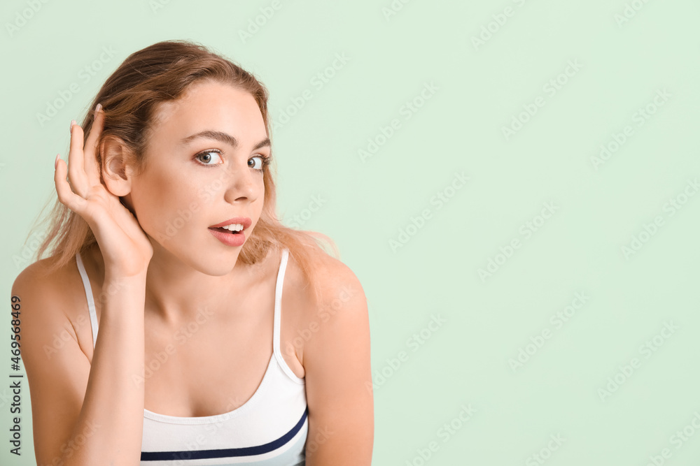 Curious young woman trying to hear something on color background Curious young woman trying to hear something on color background