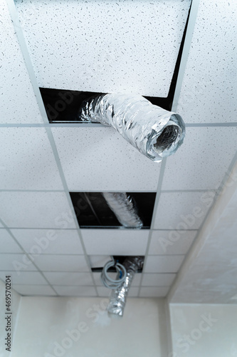 Empty industrial facility with grey wall. Internet cable hangs from the ceiling. Air conditioning tube. Closeup photo