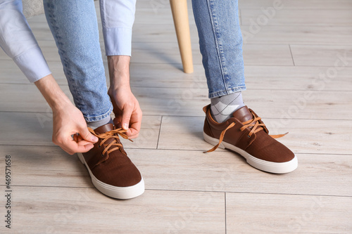 Man tying shoe laces at home