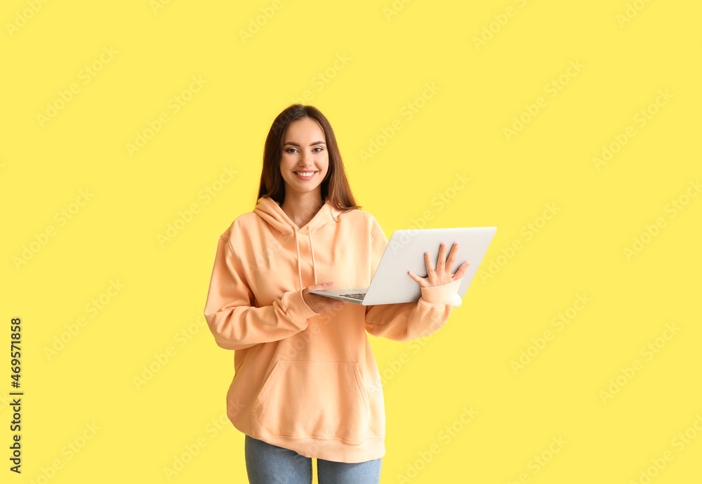 Beautiful young woman in stylish hoodie and with laptop on color background Beautiful young woman in stylish hoodie and with laptop on color background