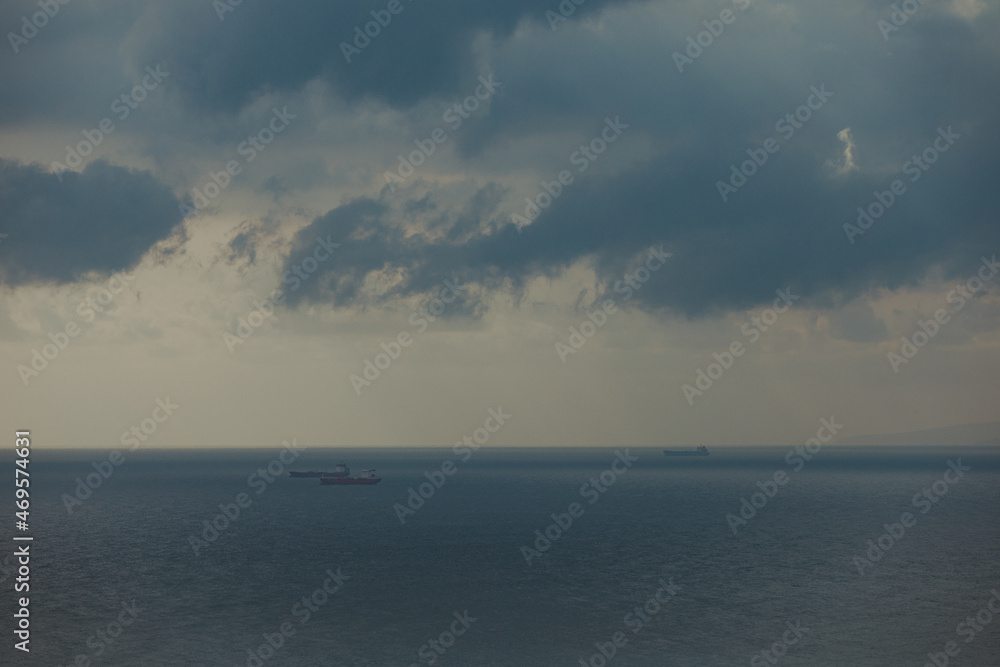 Aerial view of a single big cargo ship on the sea over cloudy blue sky