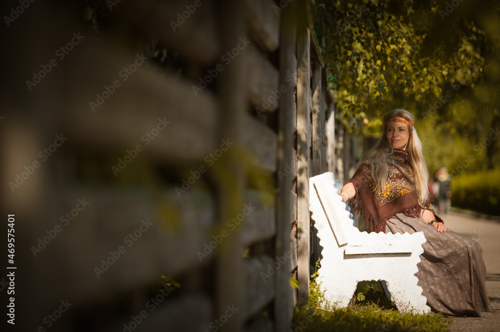 Girl in folk costume sitting on a bench in Konstantinovo