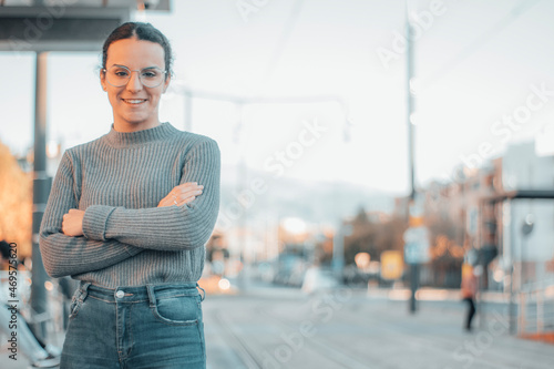 Mujer joven caminando por la estación de tren con felicidad de brazos cruzados photo