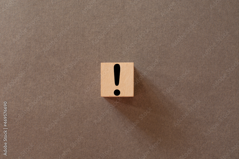 black exclamation mark on a wooden cube on a gray background black exclamation mark on a wooden cube on a gray background