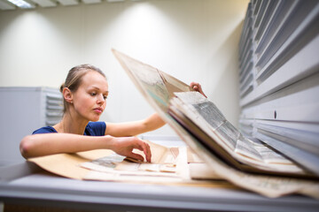 Pretty, young woman studying old maps in archives