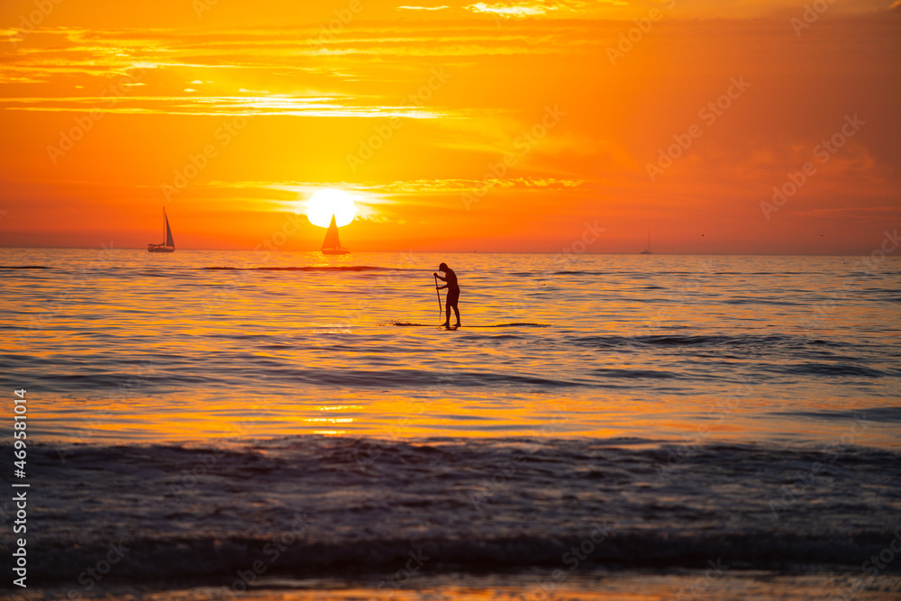 Paddle boarding. Calm sea with sunset sky and sun through the clouds over. Ocean and sky background, seascape.