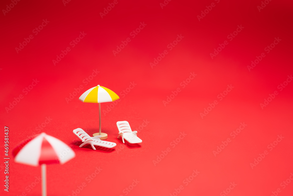 Obraz premium Two sun loungers and red umbrellas on a red background.