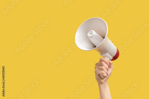 Megaphone in woman hands on a yellow background. photo