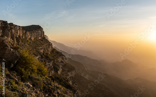 Sunrise Over Jabal Samhan's Peaks. The first light of day breaks over the rugged peaks of Jabal Samhan in Oman, casting a warm glow on the natural landscape.