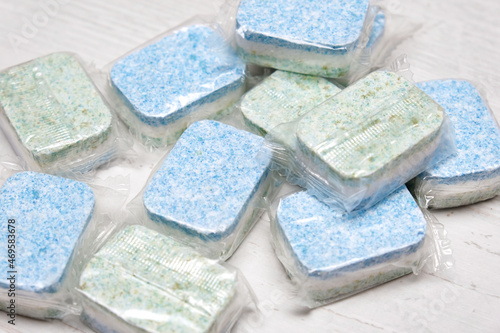 Many green and blue dishwasher tablets in water-soluble packaging close up