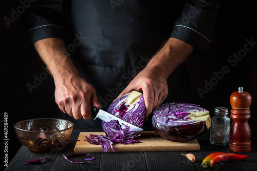 A professional chef cuts red cabbage with a knife. Cooking vegetable salad in the restaurant kitchen. Vegetable diet idea.