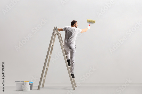 Rear view of a painter painting a wall on a ladder photo
