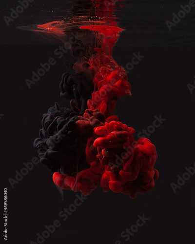 Red and black ink in water isolated on black background. Abstract background. Beautiful clouds of paint in the water.