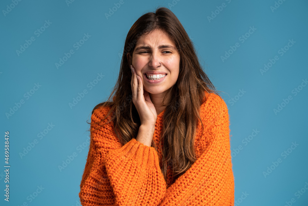 Dental problems. Portrait of unhealthy woman pressing sore cheek, suffering acute toothache, periodontal disease, cavities or jaw pain. Indoor studio shot isolated on blue background Dental problems. Portrait of unhealthy woman pressing sore cheek, suffering acute toothache, periodontal disease, cavities or jaw pain. Indoor studio shot isolated on blue background