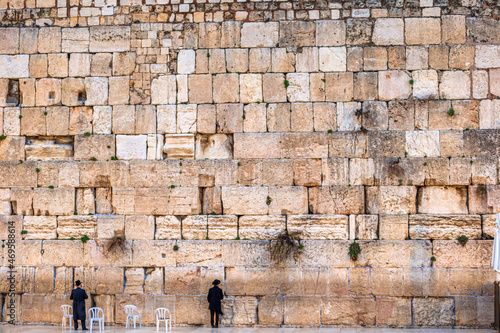 Two small man praxying at teh giant Western Wall