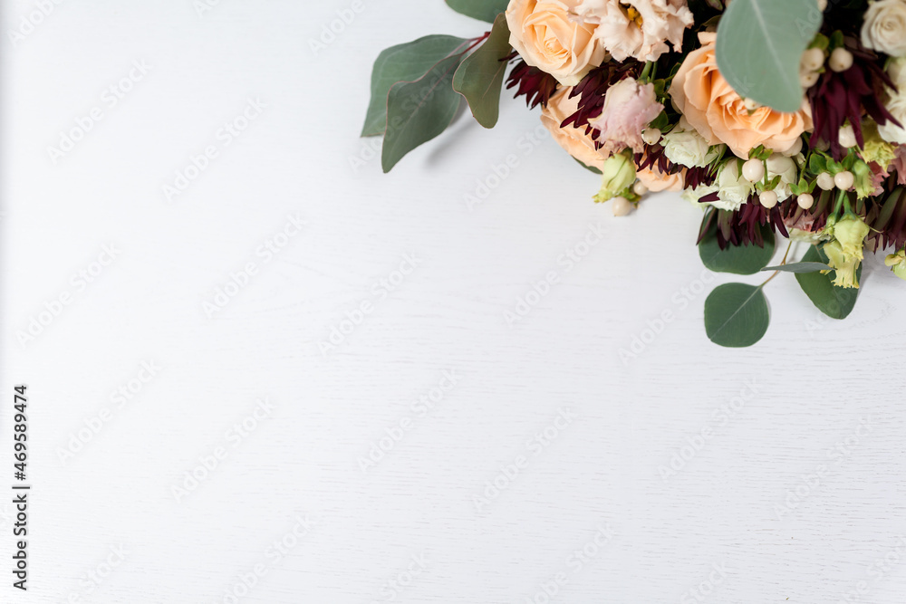 flowers and leaves on light white wooden background. blank for text