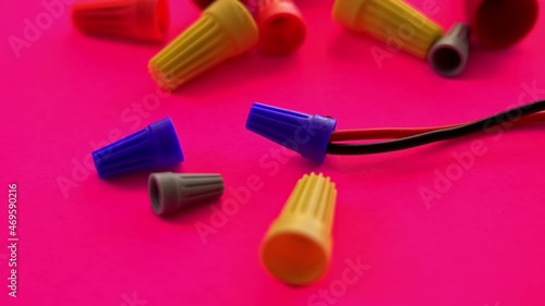 Electrician hand is taking electrical wire connector from pink background