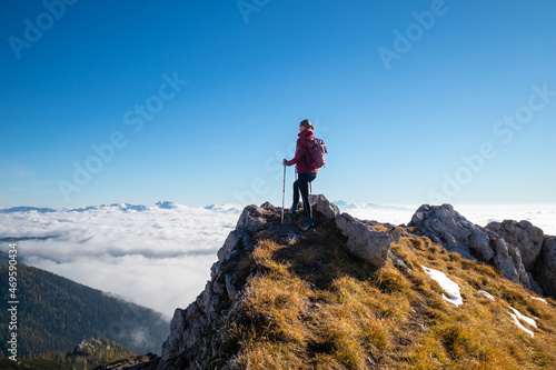 Woman on top of the mountain above the clouds bathing in sunlight.