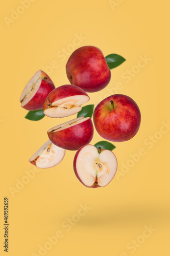 Minimal fruit concept with fresh sliced and whole apple floating in the air isolated on yellow background.