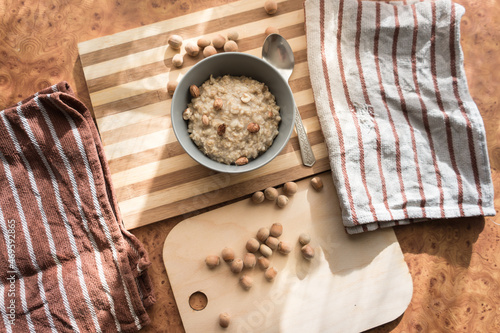 Obraz na plátne Healthy, dietary and nutritious oatmeal with hazelnuts in a gray plate on the table top view