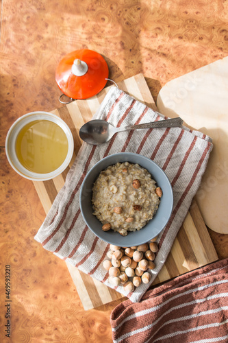 Healthy, dietary and nutritious oatmeal with delicious homemade honey, hazelnuts in a gray plate on the table top view.