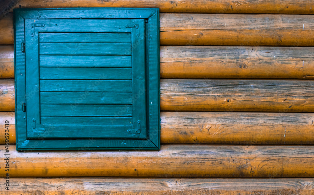 Close up of a wall of the house made of tree trunks with a blue wooden window Close up of a wall of the house made of tree trunks with a blue wooden window