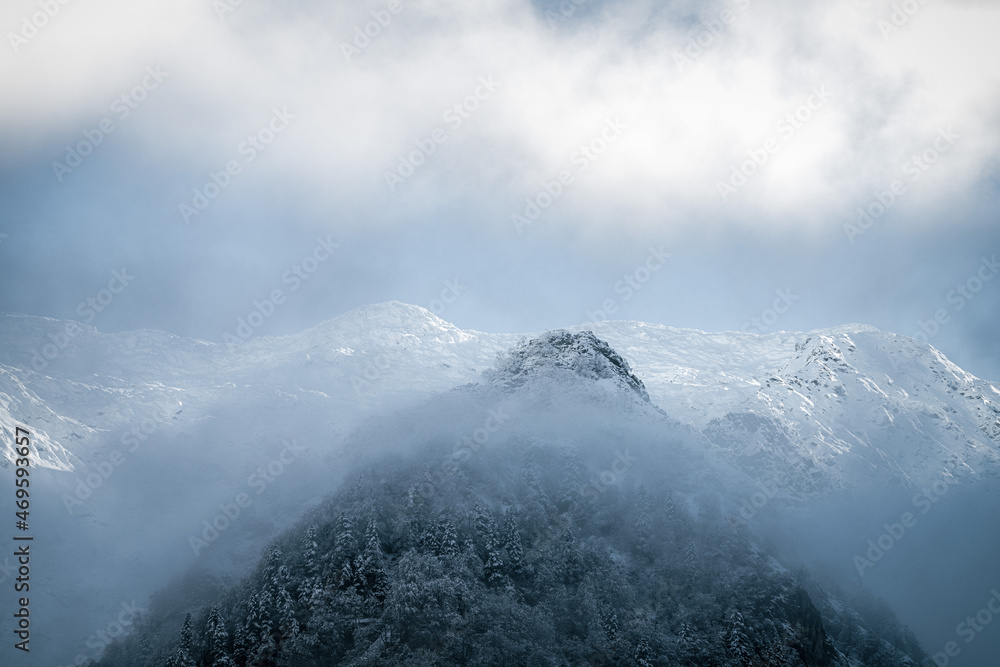 Snow-capped mountain peak emerging from the mist Snow-capped mountain peak emerging from the mist
