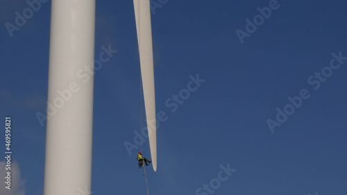 Man in Harness abseiling at tip of Wind Turbine blade, undergoing maintenance, Highest Commercial Wind Turbine at 126 metre in the United Kingdom photo