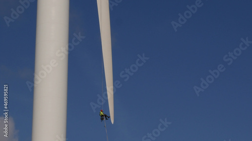 Photos Man in Harness abseiling at tip of Wind Turbine blade, undergoing maintenance, H