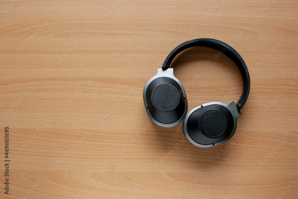 View from above of a black headphones on the wooden table View from above of a black headphones on the wooden table