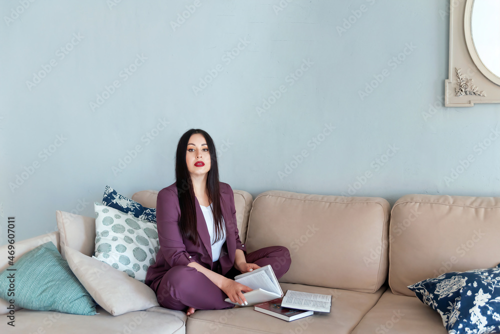 portrait of a beautiful young woman on the sofa next to several books during home schooling portrait of a beautiful young woman on the sofa next to several books during home schooling