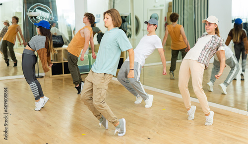 Group of interested confident teenagers training movements of modern street dance in choreography class